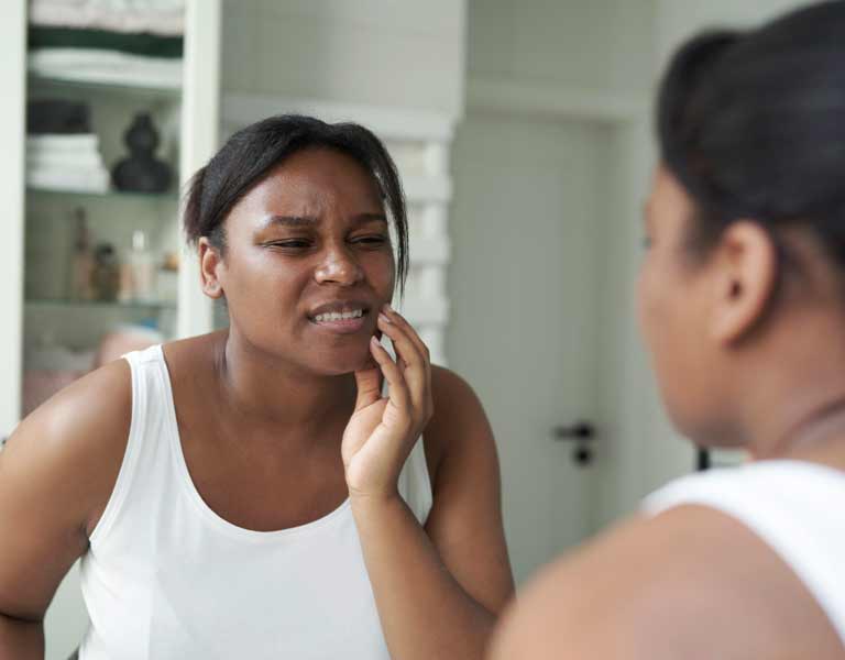 African-American woman experiencing severe bruxism in the bathroom in Stafford, VA