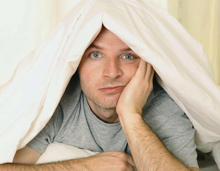 Man lying in bed with eyes open suffering from sleep apnea in Stafford, VA