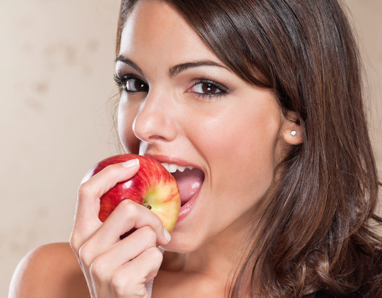 Woman biting an apple and showing healthy teeth in Stafford, VA