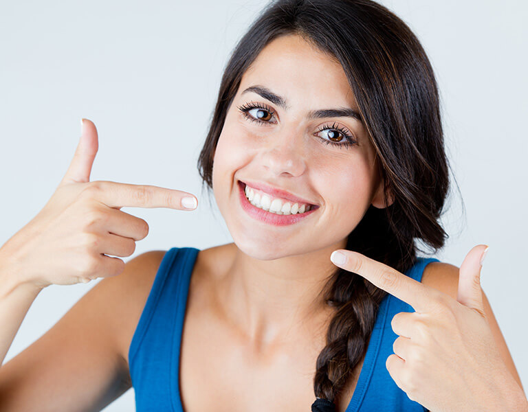 A woman pointing to her teeth at a dental clinic in Stafford